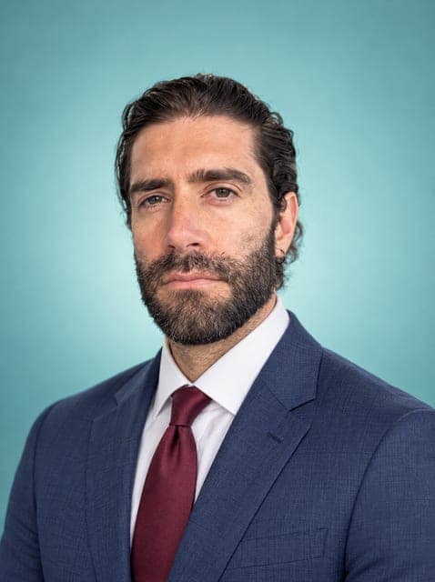 Professional headshot in a navy suit and tie